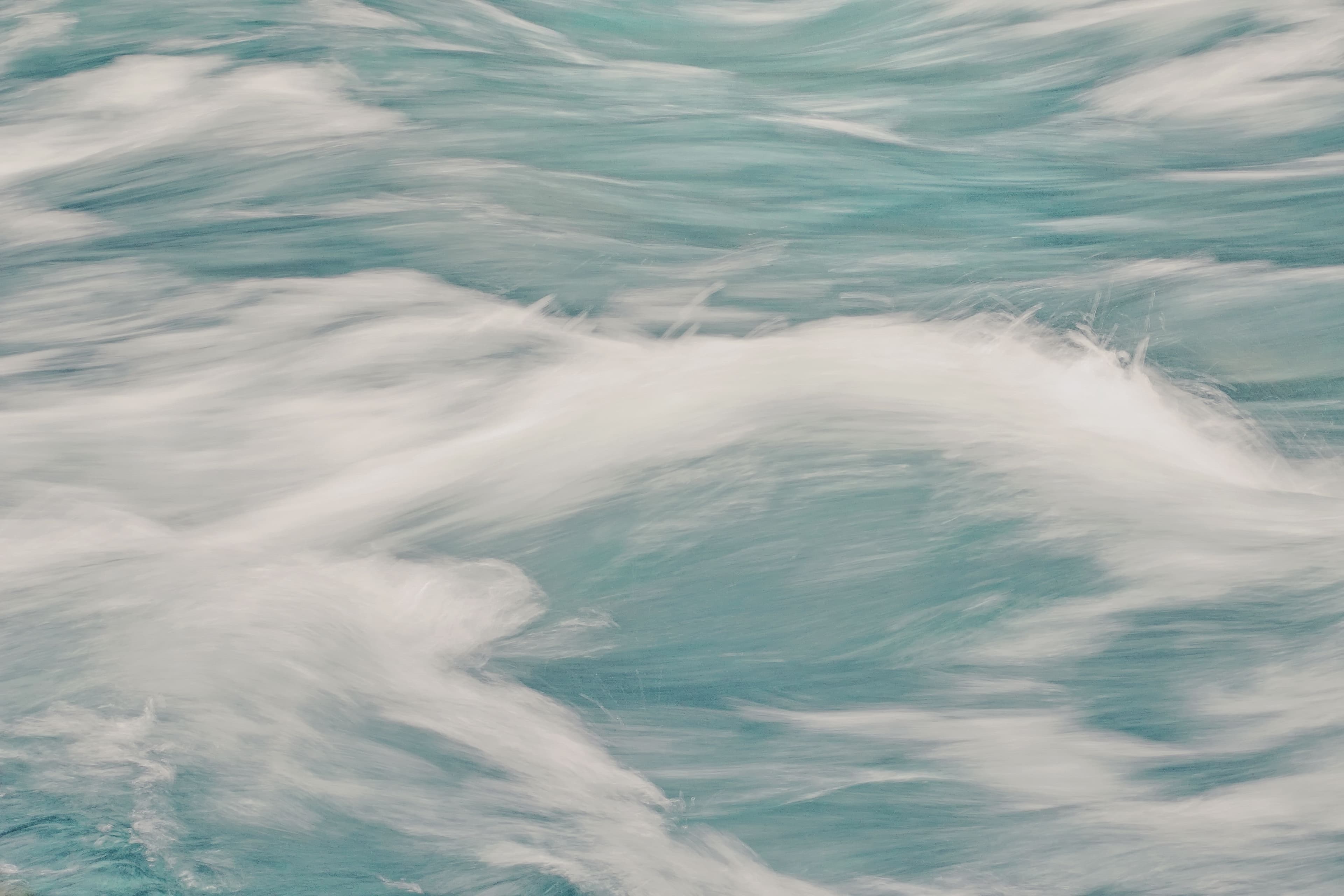 Soft turquoise ocean waves flowing into one another